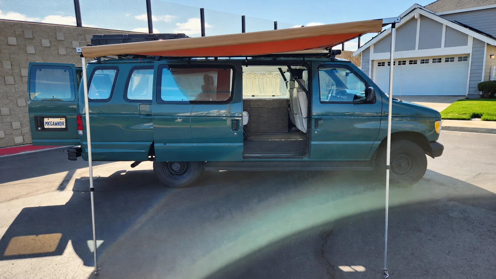 Green Walter campervan with an orange side awning extended; its rear plate reads MKGAWNDR.