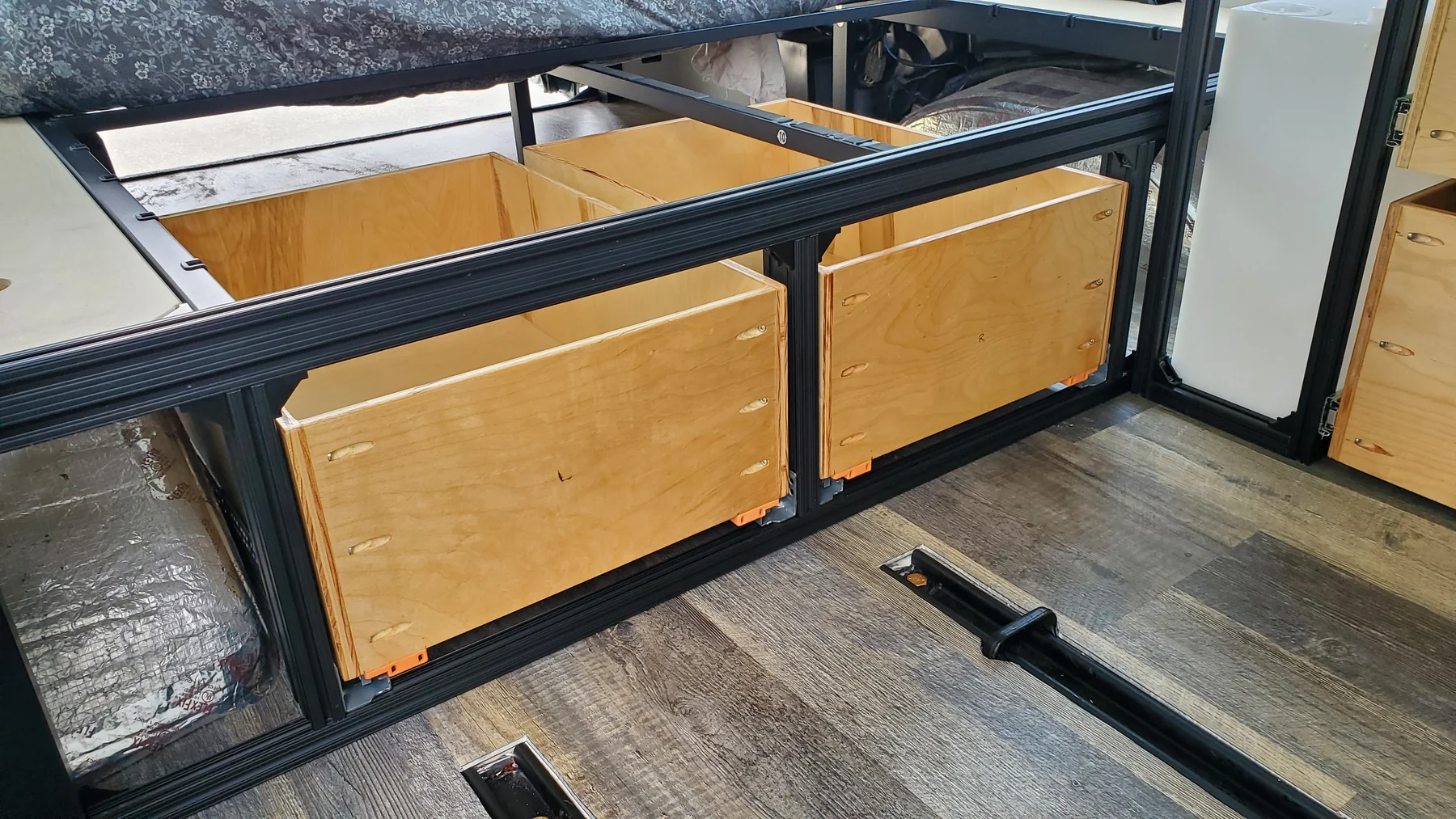 Two light plywood drawer boxes with visible pocket holes fitted into black under-bed frame openings.
