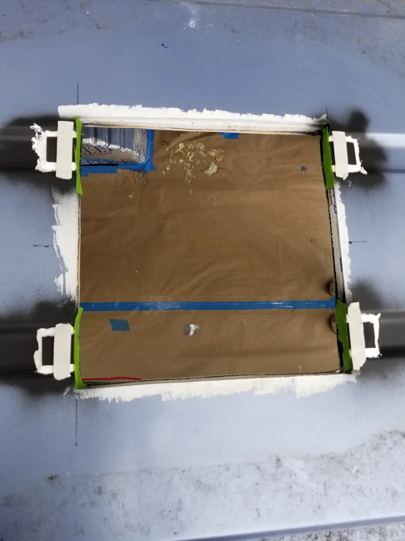 Roof opening with small white blocks, green tape and perimeter treatment exposed.