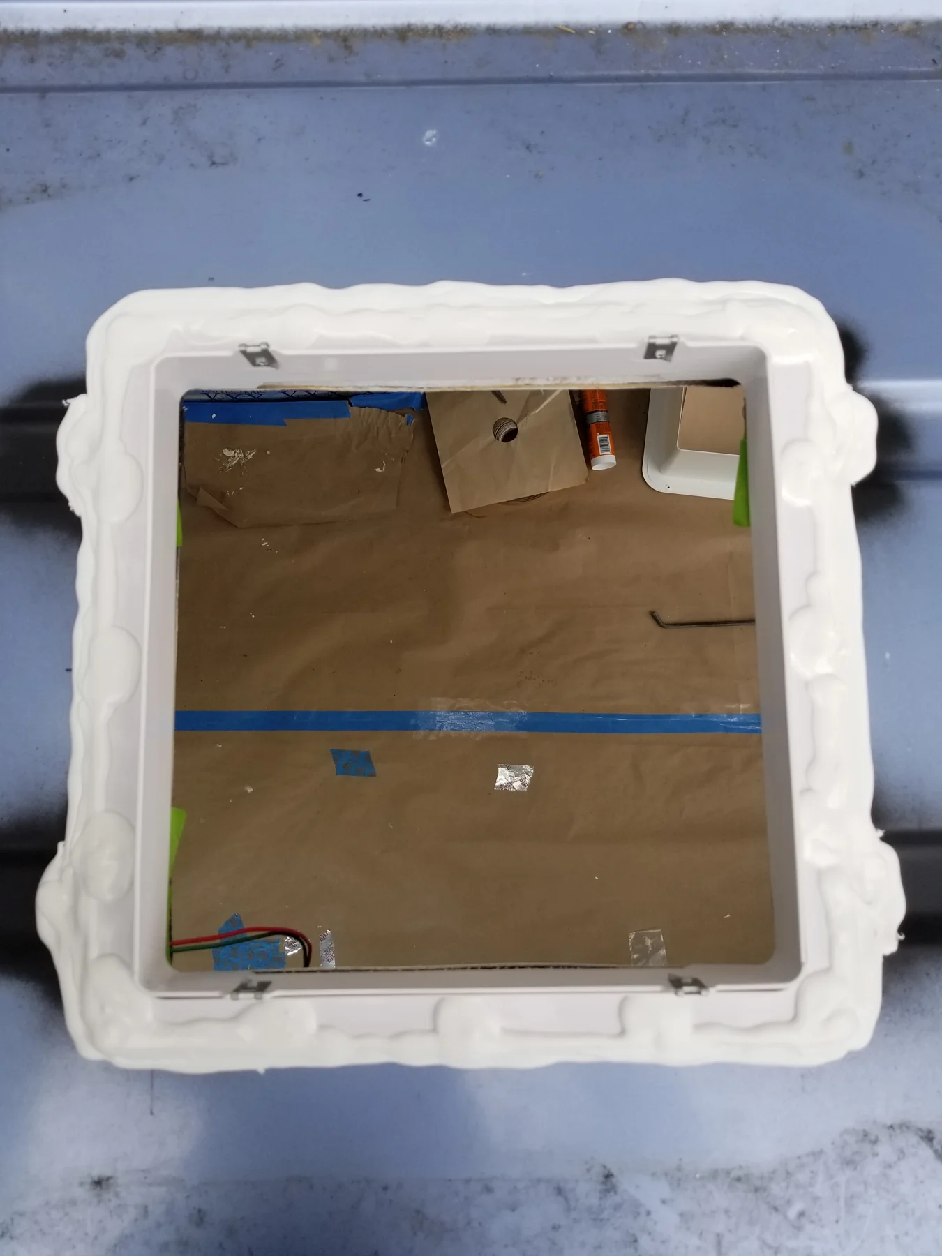 White roof fan receiving flange with visible metal clips around a protected opening.