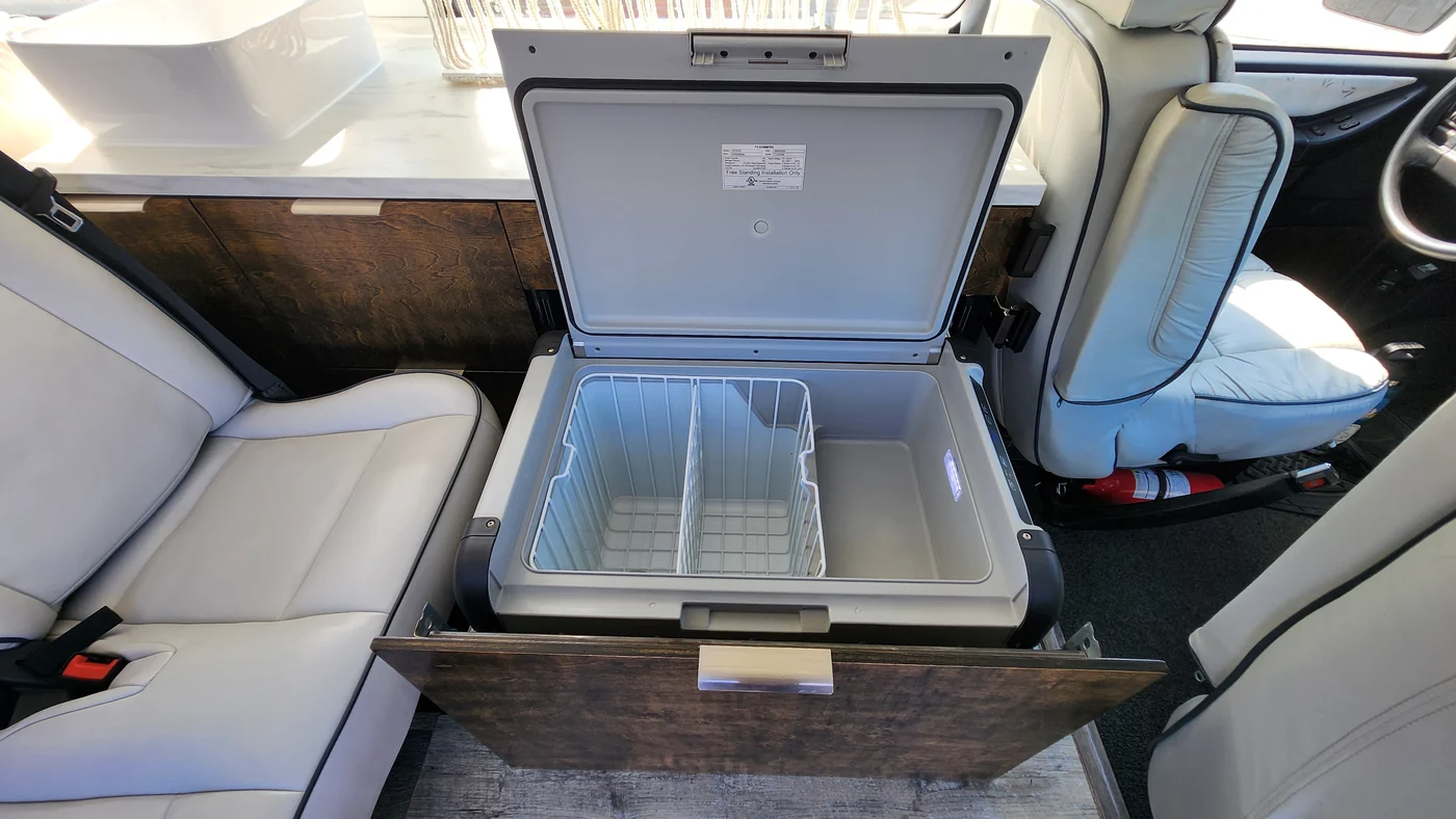 Open Dometic cooler on its pull-out tray below the kitchen counter.