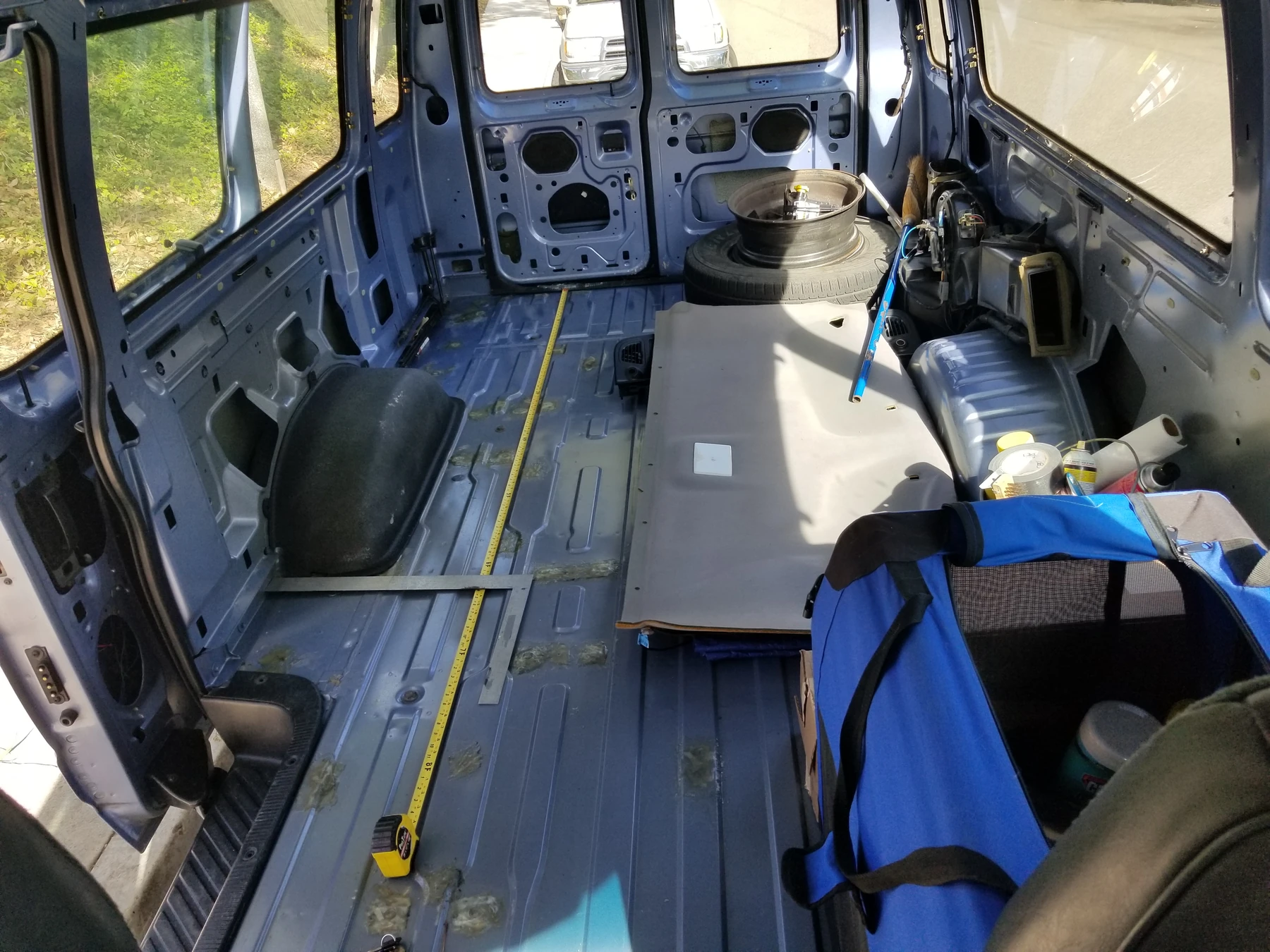 Measuring tools and loose panels arranged on the floor inside the partly stripped van.