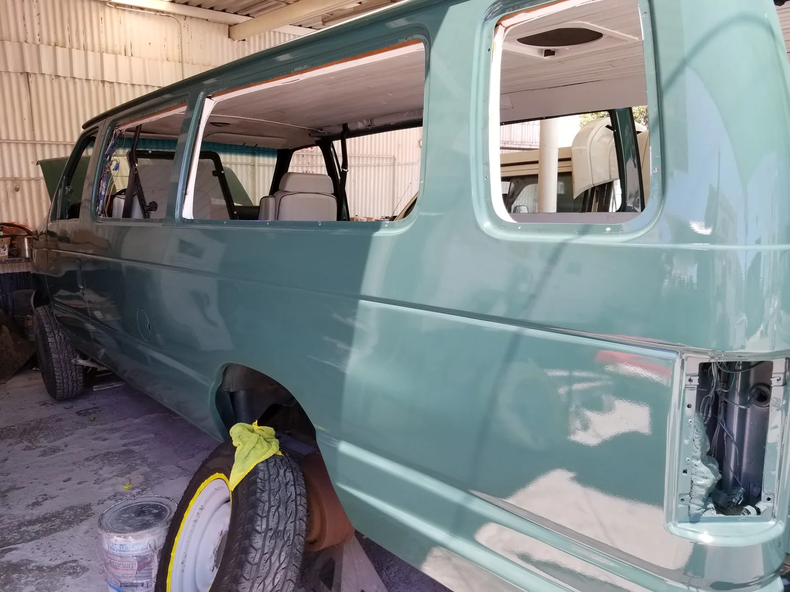 Green side and rear-quarter of Walter in a workshop, with side glass and rear lamp removed.