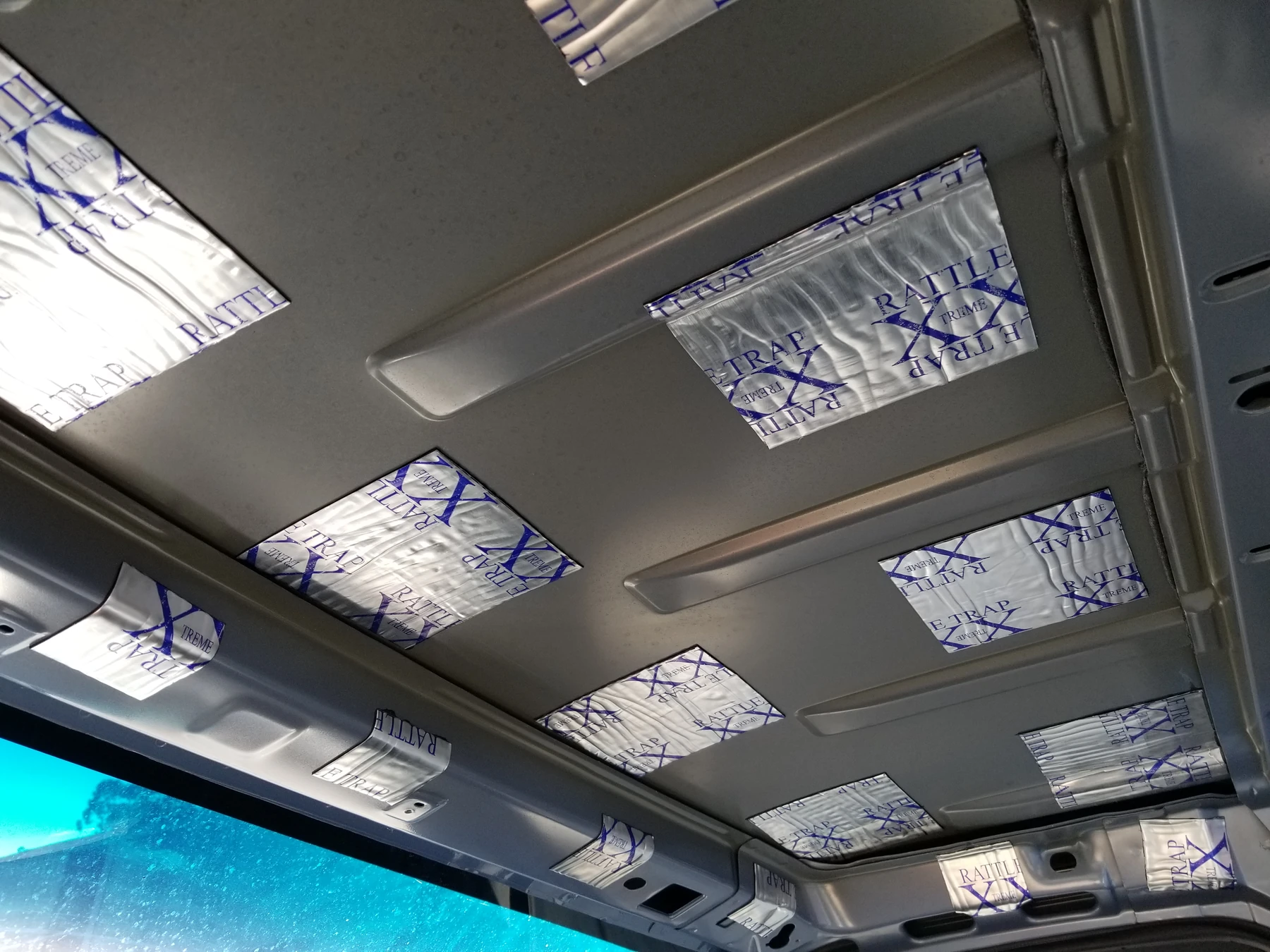 Separate foil-faced damping patches between visible blue-gray roof ribs.