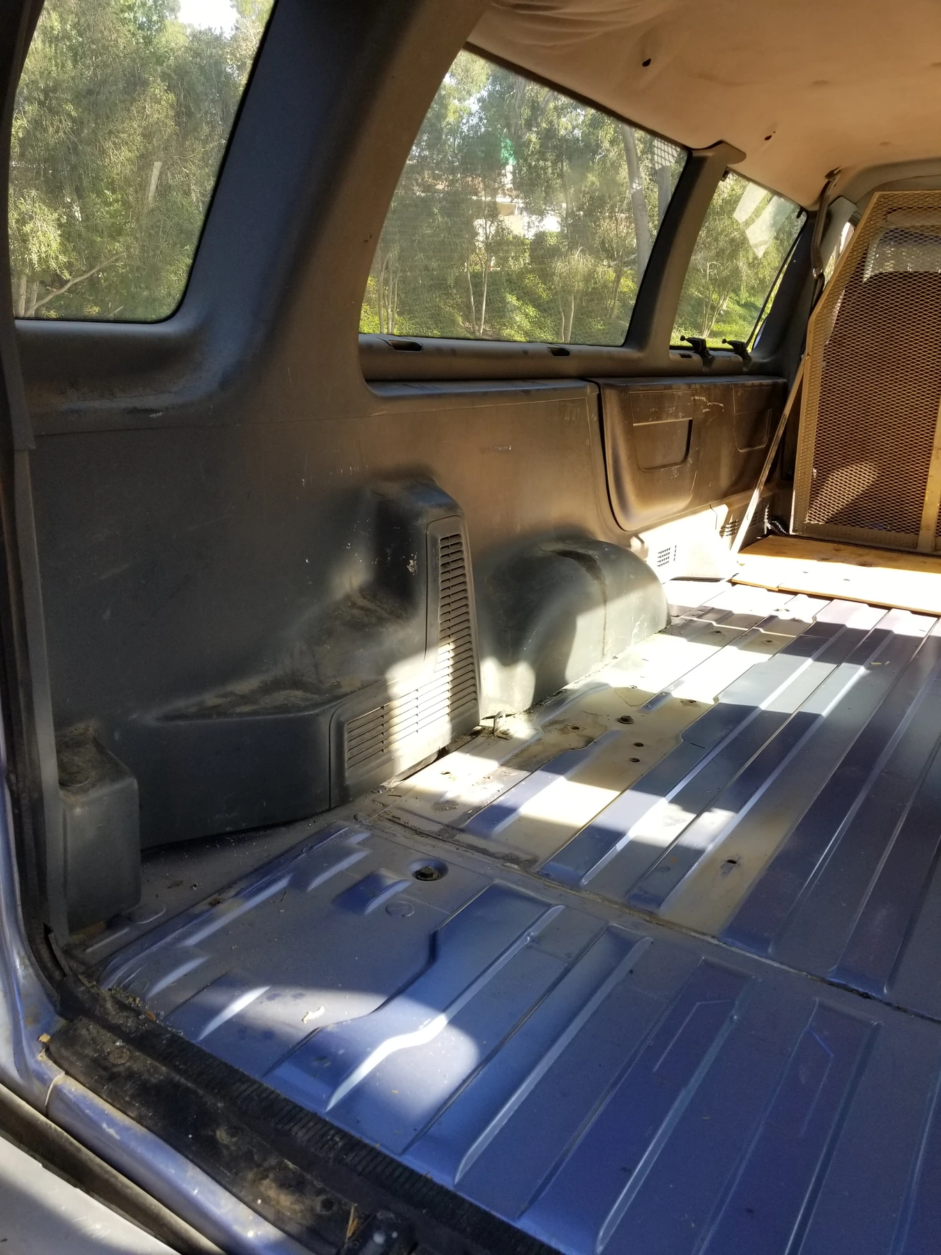 Blue ribbed steel floor exposed inside the van after carpet removal.